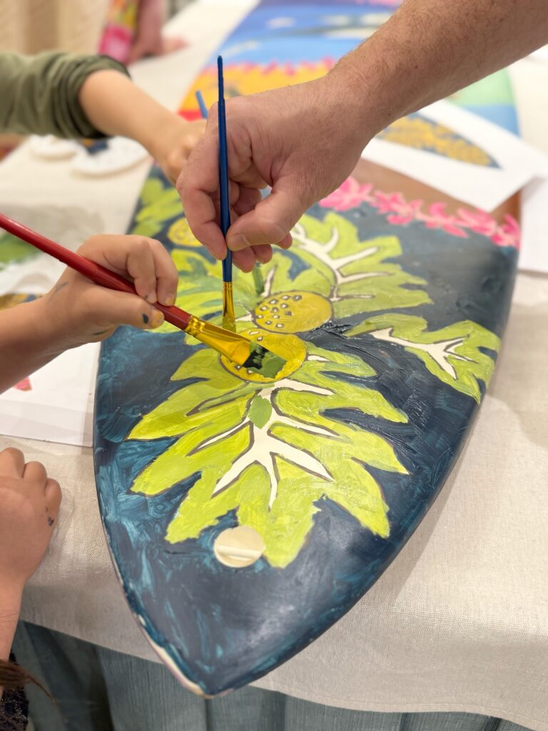 Guests painting the community surfboard during artist residency at the Ritz-Carlton in Kapalua.