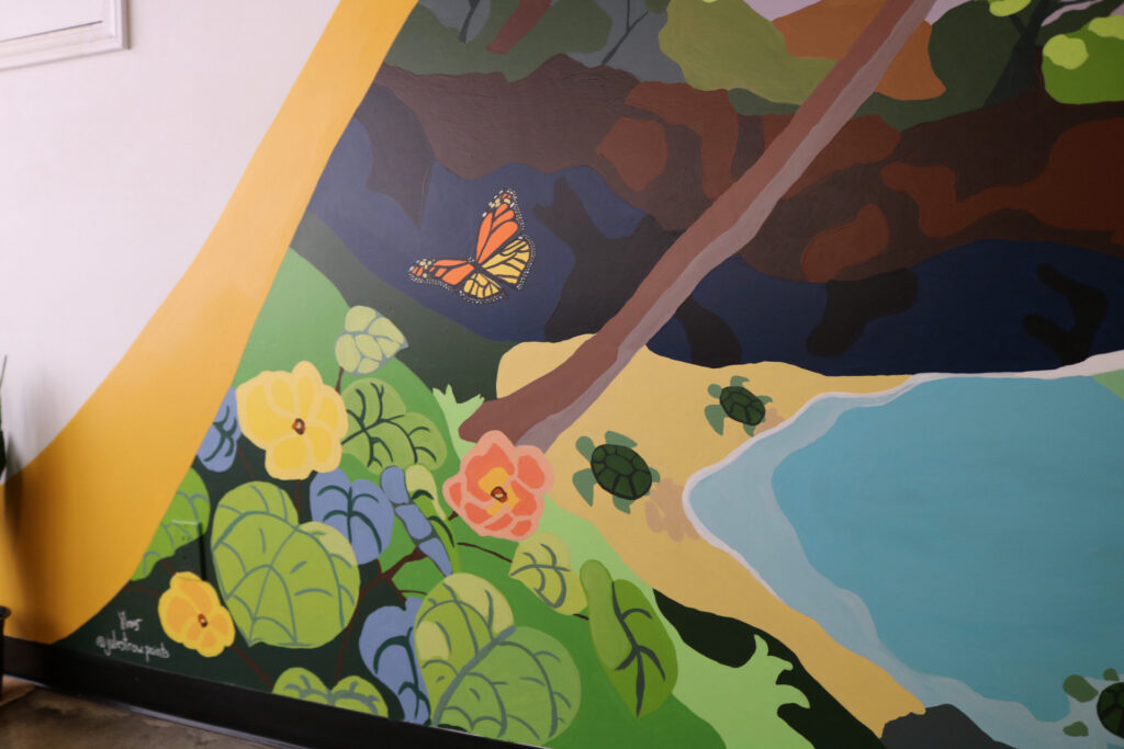 Turtles, a monarch butterfly and native plants painted in a mauimural in makawao town.